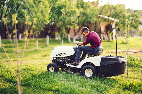 Dettagli di giardinaggio, giardiniere industriale che lavora con tosaerba da corsa e erba da taglio in giardino — Foto Stock