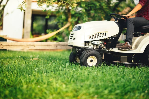 Detalles de paisajismo - trabajador que utiliza tractor profesional para cortar y recortar hierba —  Fotos de Stock