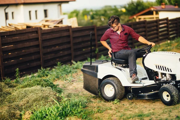 Mannen med gräsklippare, professionella arbetare skära och lossning gräs — Stockfoto