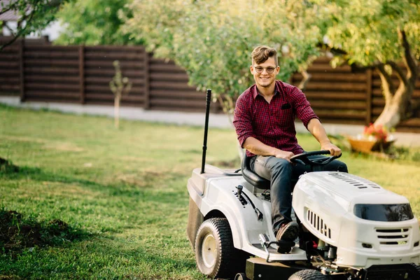 Smiling man riding a lawnmower and doing landscaping works — Stock Photo, Image