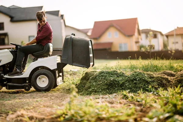 Людина використовує газонокосарку і обрізає траву в саду під час вихідних — стокове фото