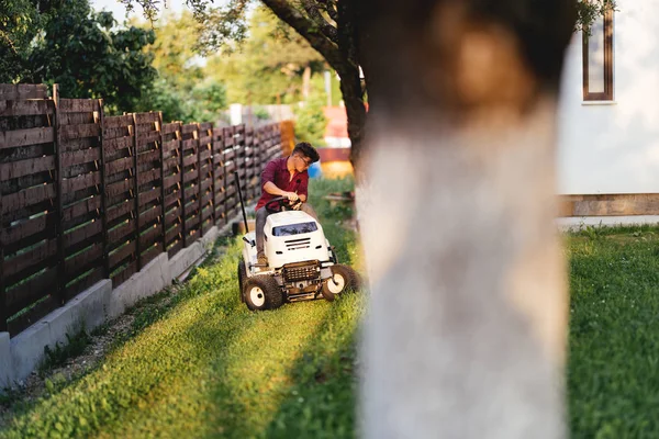 Trabajador masculino montar cortacésped y recortar la hierba en el jardín — Foto de Stock