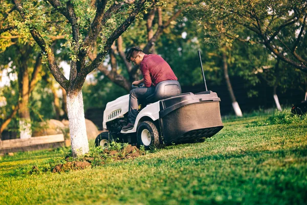 Maschio lavoratore con attenzione potatura prato. Occupazione tagliaerba in campo industriale — Foto Stock