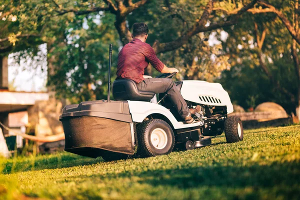 Trabajador profesional que usa cortacésped para cortar hierba en el jardín — Foto de Stock