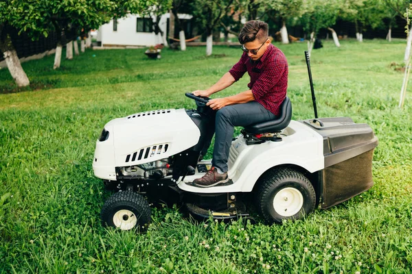 Gardner trimmen en modelleren van de tuin met behulp van een ritje op grasmaaier — Stockfoto