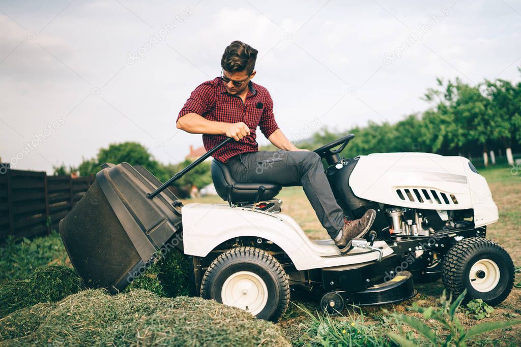 Gardner doing landscaping works and cutting grass, unloading grass