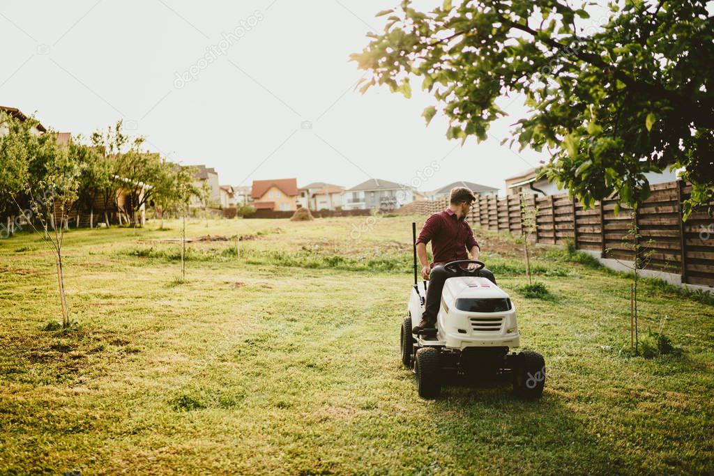 vintage effect of landscaping works. Male worker riding a tractor grass trimmer