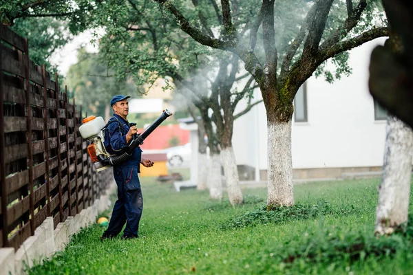 L'homme pulvérise des pesticides toxiques et des ierbicides dans les vergers fruitiers — Photo