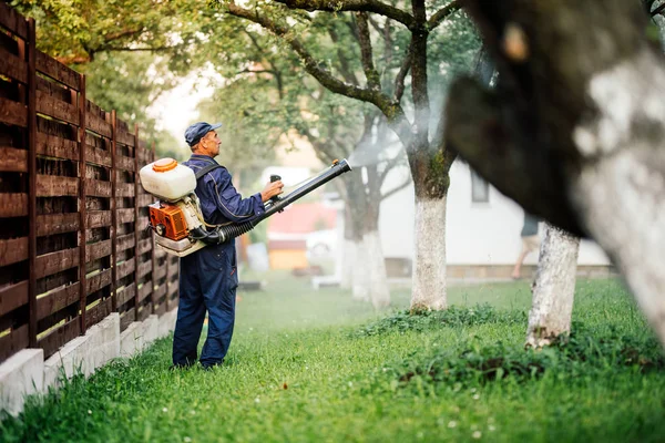 Bonde arbetare sprutar bekämpningsmedel behandling på fruktträdgård — Stockfoto