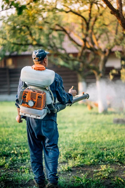 Landbouw bedrijfsmedewerker organische pesticiden sproeien op fruitteelt tuin — Stockfoto