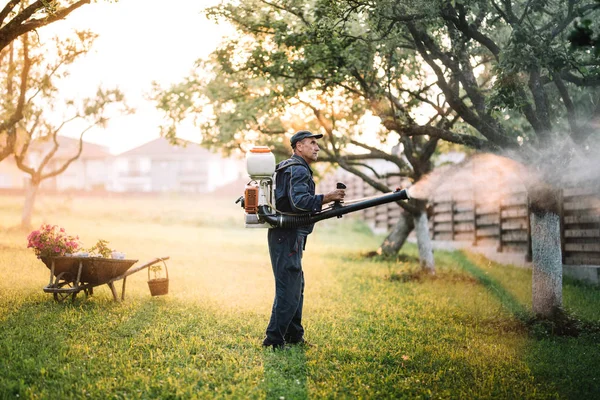 Farmer working with spraying machine in fruit orchard — Stock Photo, Image