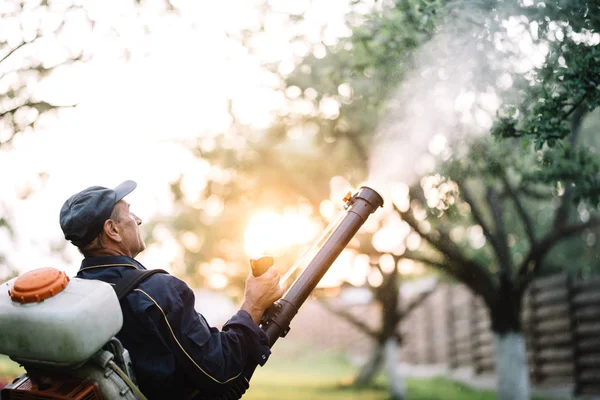 Farmář, tvrdá práce údržbář pomocí batoh stroj pro postřik organické pesticidy — Stock fotografie