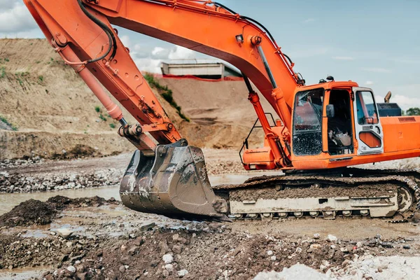 Heavy duty industrial excavator working during earthmoving works at highway construction site