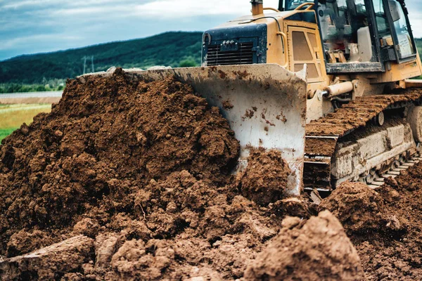 Yellow mini bulldozer working with earth and soil while doing landscaping works on construction site — Stock Photo, Image