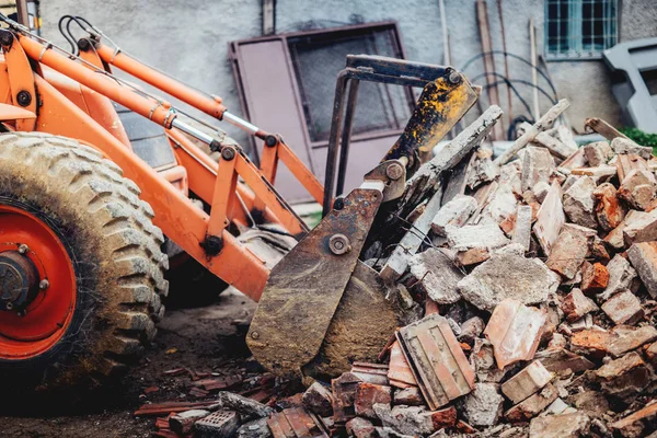 Excavadora demoliendo un edificio viejo y llevando escombros en camiones volquete — Foto de Stock