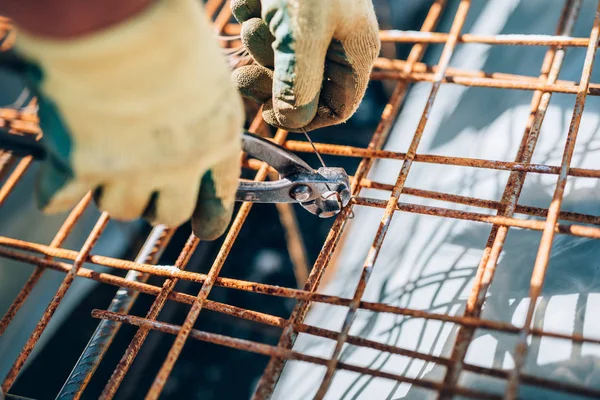 Details van stalen versterking op de bouwplaats. Industriële bouwvakker met behulp van Tang en draad ro — Stockfoto