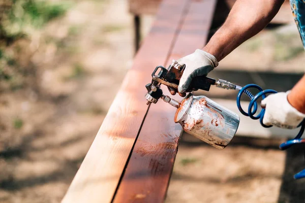 Mãos de trabalhador na indústria de carpintaria. Pintura manual de madeira com tinta marrom — Fotografia de Stock