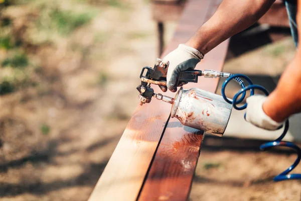 Travailleur de la construction utilisant pistolet à peinture et peinture brune pendant les travaux de rénovation. Clôture de peinture — Photo