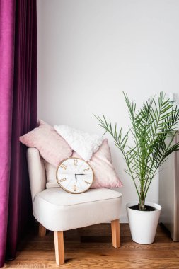 Modern oturma odasında mor perdeler, rahat koltuk, yastık ve tv standı