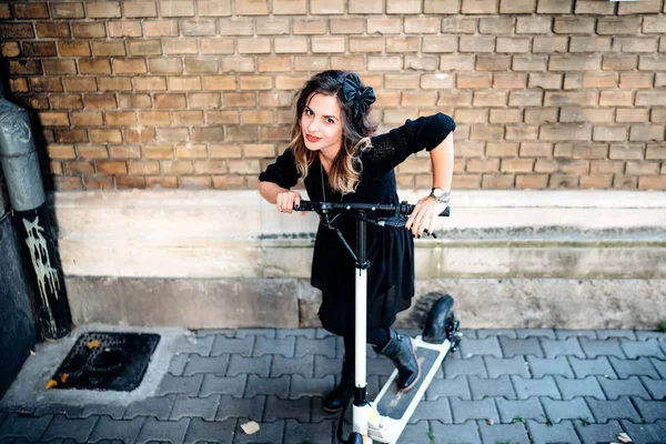 Mulher alegre relaxante e sorridente ao posar e andar de scooter elétrico. Retrato de menina sorridente — Fotografia de Stock