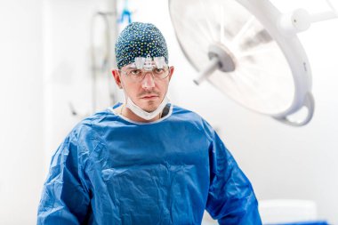Cerrah hastane ameliyat odasında çalışma steril ekipmanları ve ameliyat lambaları ile portresi. 