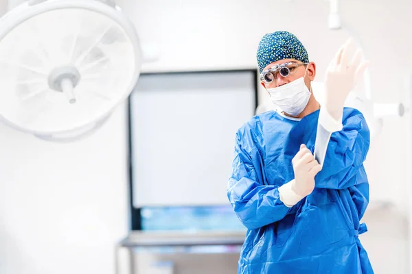 Portrait of plastic surgeon wearing scrubs and protective rubber gloves in operating room — Stock Photo, Image