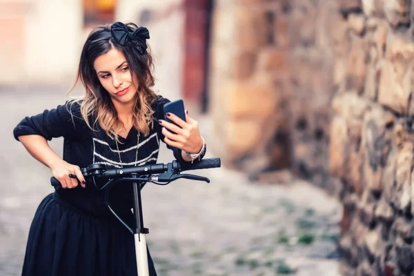 Detalles del estilo de vida: retrato de una mujer tomando selfie con un teléfono inteligente, relajándose en una scooter eléctrica — Foto de Stock