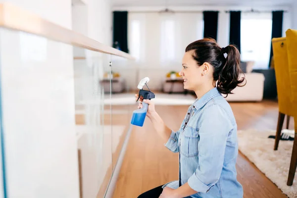 Nahaufnahme Porträt einer modernen Frau bei der Hausarbeit im Haus. Frau reinigt Glas mit Spülmittel und Tuch — Stockfoto