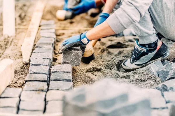 Industriarbetare banar väg med granit gatsten med sand och gummiklubba — Stockfoto