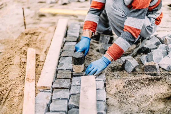 Operaio edile utilizzando strumenti industriali per pavimentazione in pietra. blocchi di granito installare dettagli — Foto Stock