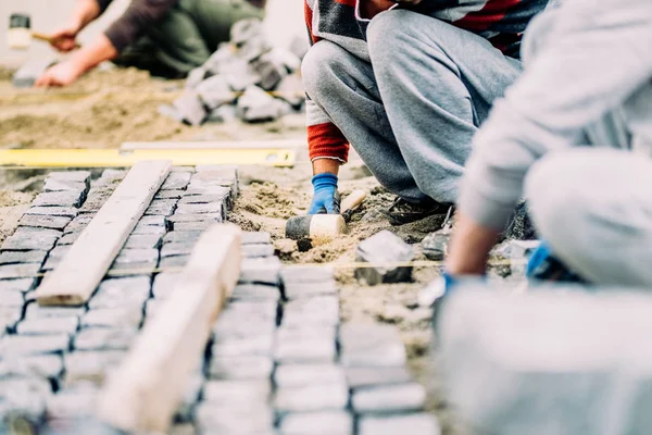 Manliga arbetare, handyman och byggande arbetare installera kullerstensbelagda trottoaren på sökväg, trottoar eller road — Stockfoto