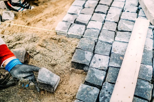 Primer plano de manos de albañil utilizando piedras de granito para crear pavimento —  Fotos de Stock