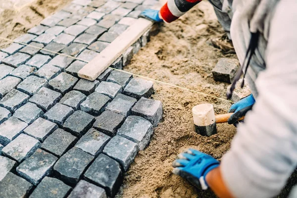 Industrielle Details der Baustelle - Arbeiter verlegen Granitsteine als Fußweg — Stockfoto