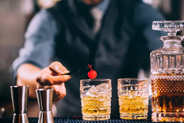 Barman preparando cóctel a la antigua, adornando con cereza. vintage imagen filtrada — Foto de Stock