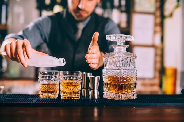 Close up of barman hands adding ice and whiskey to modern urban cocktails. Sky bar serving elegant drinks — Stock Photo, Image