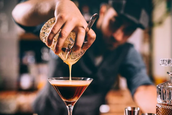 Close up of barman hand pouring alcoholic cocktail in martini glass — Stock Photo, Image