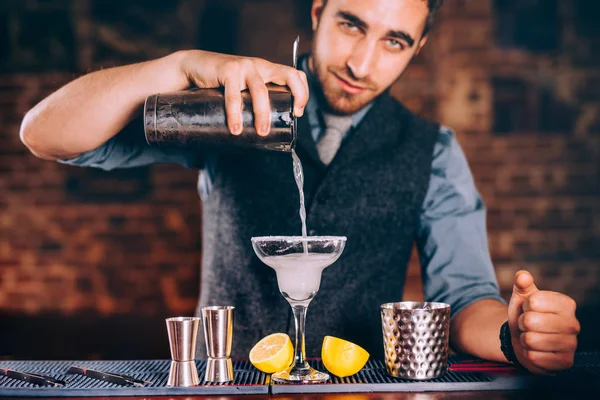 Retrato de barman bonito usando ferramentas de bar para coquetéis alcoólicos. Margarita com tequila, fatia de limão e gelo — Fotografia de Stock