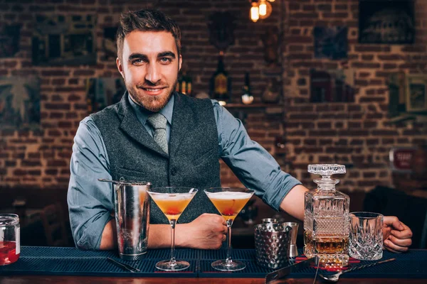 Schöner lächelnder Barkeeper, der die Arbeit genießt und Cocktails an der Bar zubereitet — Stockfoto