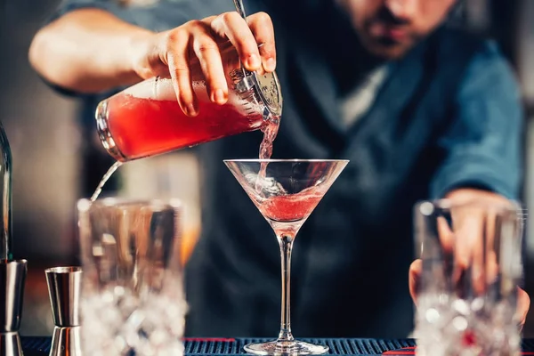 Close up details of barman pouring vodka cosmopolitan cocktail in martini glass — Stock Photo, Image