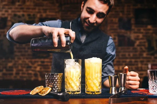 Barman profissional preparando coquetéis e derramando álcool fresco em copos. Cocktails servidos em bar, restaurante ou pub — Fotografia de Stock