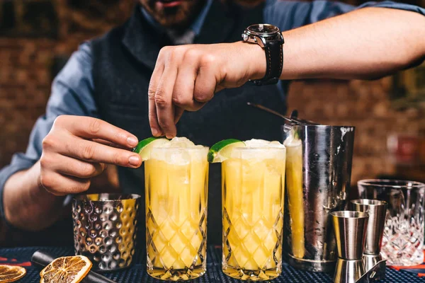 Nahaufnahme von Barmannhänden, die ausgefallene Cocktails garnieren und zubereiten. Orangencocktails auf Wodkabasis an der Bar — Stockfoto