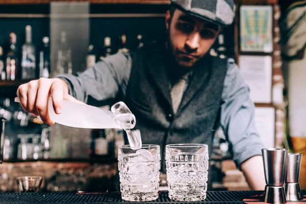 Barman preparando coquetéis, derramando gelo e wiskey em bebidas alcoólicas frescas — Fotografia de Stock