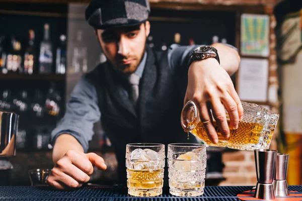 Barman derramando coquetel de uísque em copos de cristal — Fotografia de Stock