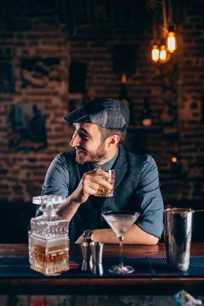 Cheerful bartender enjoying an alcoholic drink at pub, bar or restaurant. Evening relaxation concept — Stock Photo, Image