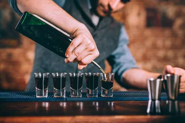 Porträtt av professionella bartendern hälla alkoholhaltiga digestif i shot glasögon på bar — Stockfoto