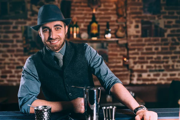 Close up portrait of elegant and stylish bartender wearing hat and vintage clothes while preparing drinks and cocktails — Stock Photo, Image