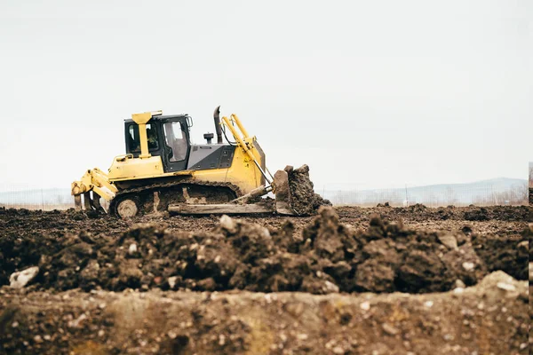 Mini industrial bulldozer moving dirt and earth with scoop. Industrial details of landscaping — Stock Photo, Image