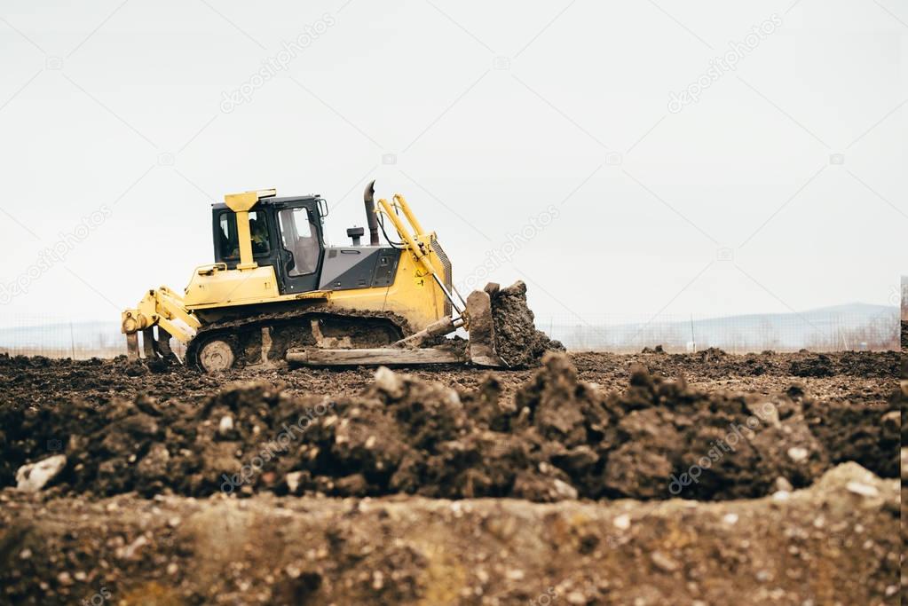 mini industrial bulldozer moving dirt and earth with scoop. Industrial details of landscaping