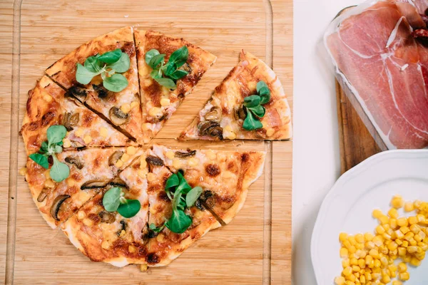 Slices of pizza and fresh ingredients on white table in new home kitchen — Stock Photo, Image