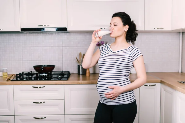 Portrait de belle femme enceinte buvant un verre de lait dans une nouvelle cuisine — Photo